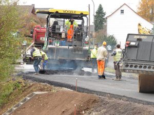 Der Übergang zur alten Straßendecke muss per Hand planiert werden